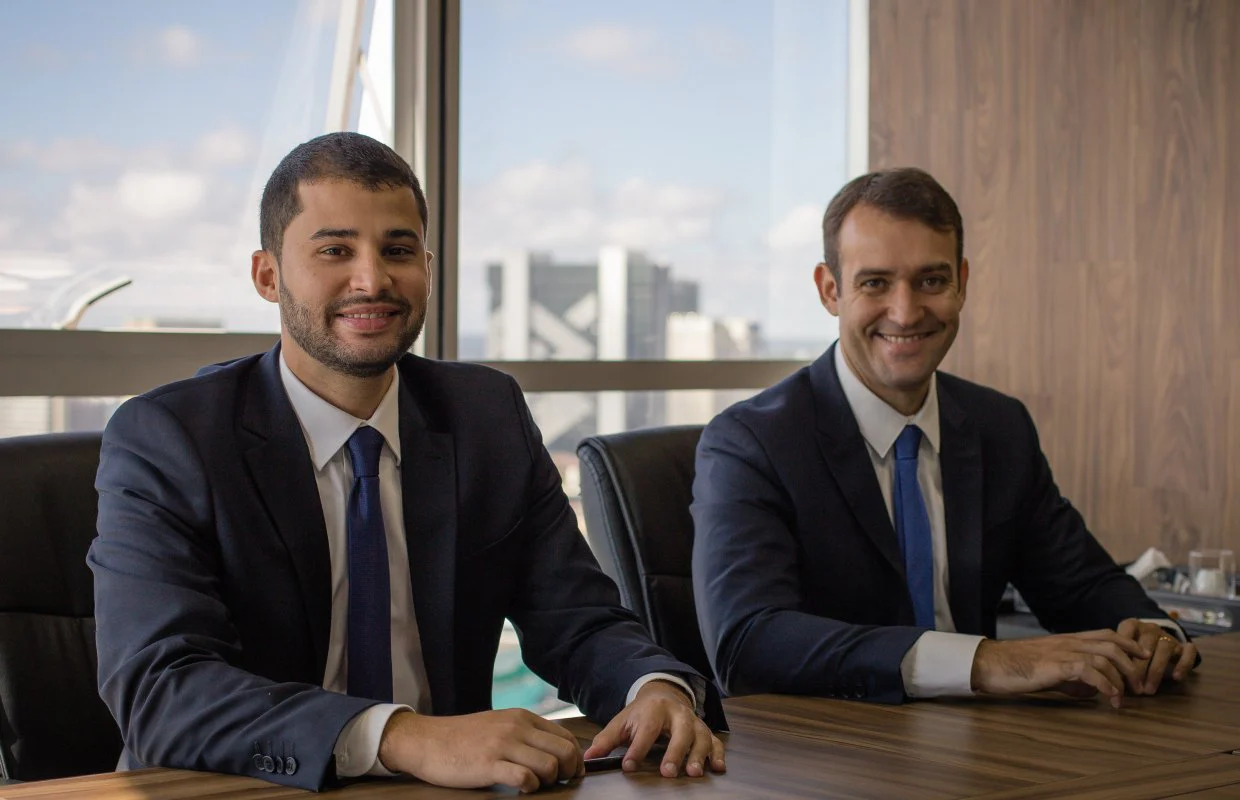 Nathaniel e Mateus, sócios da Confiança Wealth, sentados à mesa do escritório